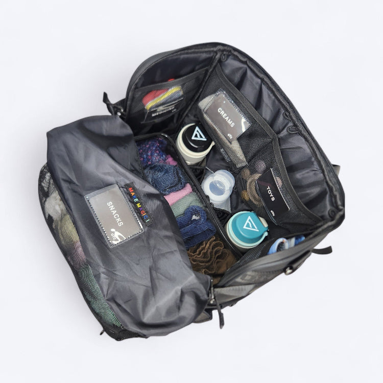 OUT YNDR CLUB Medley nappy bag, black colour, top open view showing lots of pockets and compartments filled with baby bottles and clothes and nappies