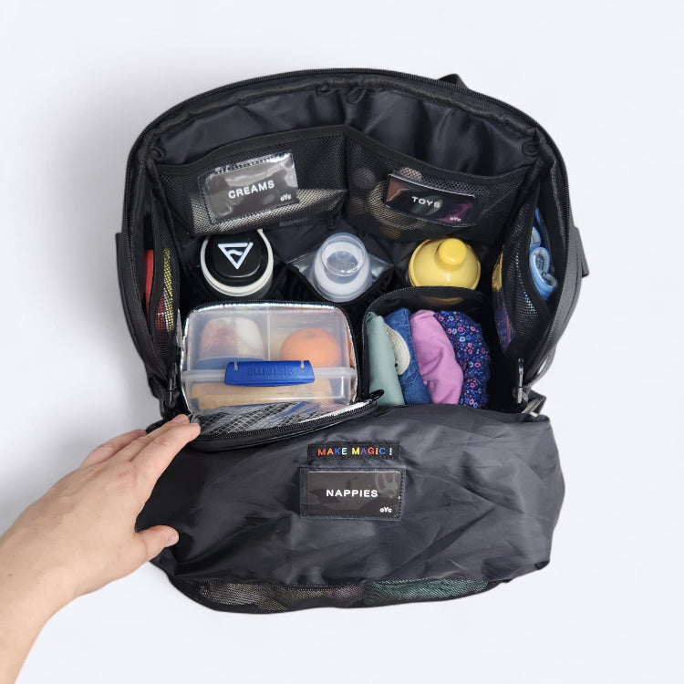 OUT YNDR CLUB Medley baby bag, top view open packed with baby items, food and clothes